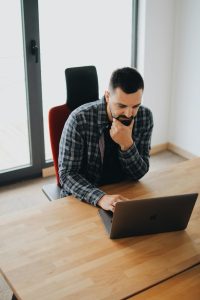 A thoughtful software developer sitting at a desk, working on a laptop, symbolizing the process of green software development and sustainable IT practices