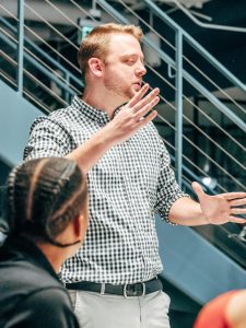 A man passionately speaking to colleagues during a meeting, representing leadership and collaboration in promoting sustainable IT and green software development practices.