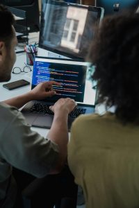 A man and a woman who are developers working on code. 