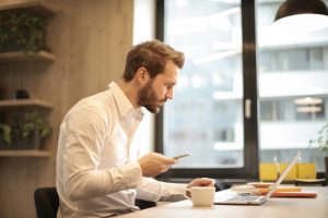 Image of a male office worker going through the ISO standards on his laptop.